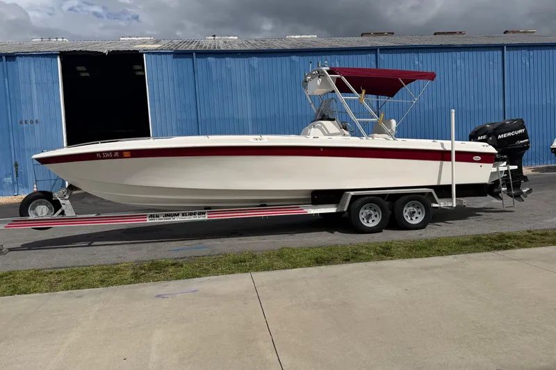 The Image of 1997 Wellcraft 302 Scarab Sport boat on trailer, parked near blue warehouse. - 1