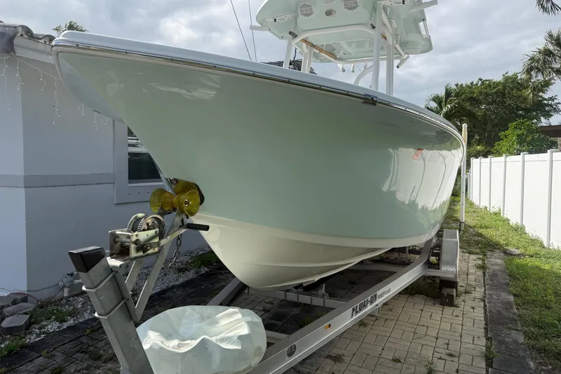 Slide: The Image of 2023 Sea Pro 219 Deep V CC boat on trailer, parked beside a house. - 2