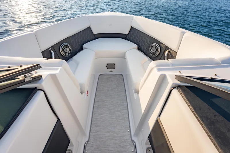 Slide: The Image of 2026 Four Winns H2 OB boat interior with cushioned seating and speakers, on calm water. - 25