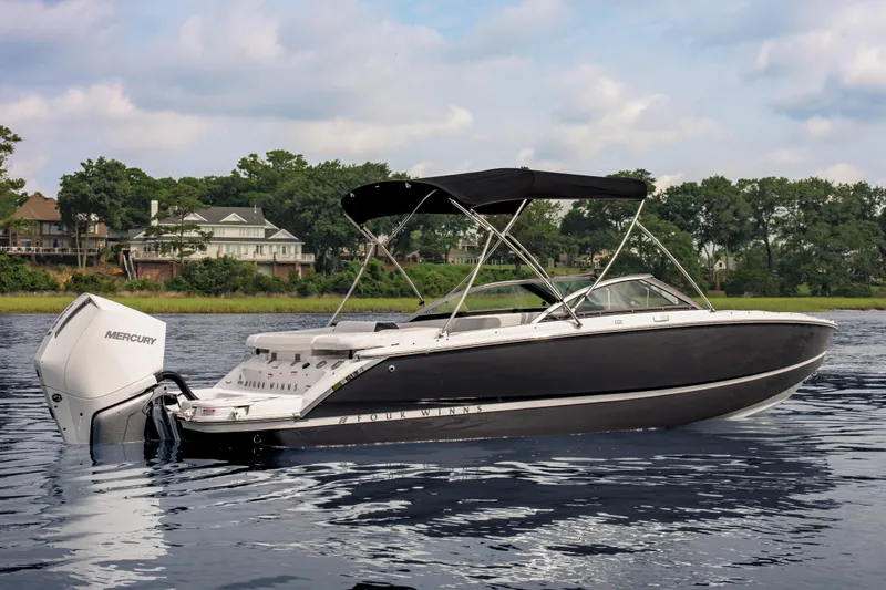 Slide: The Image of 2026 Four Winns H2 OB boat with Mercury outboard engine on a serene lake. - 2
