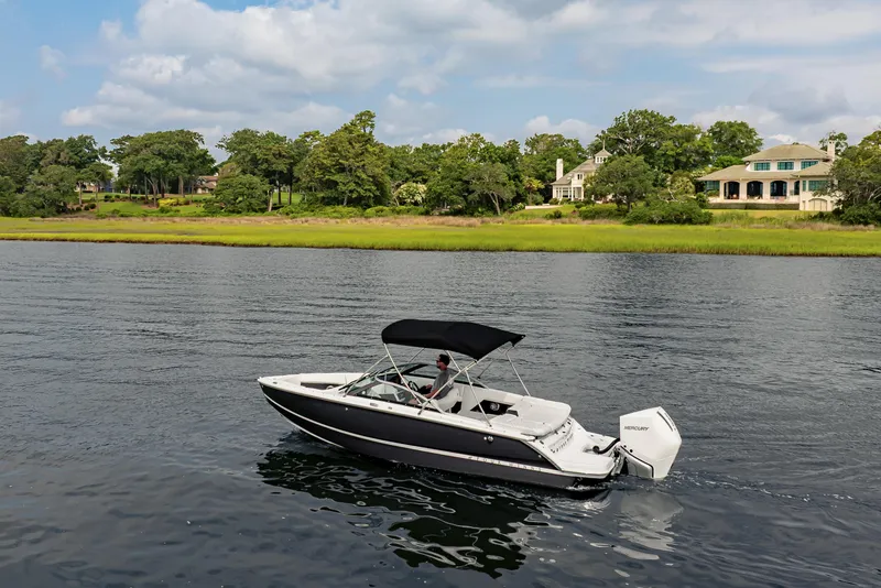 Slide: The Image of 2026 Four Winns H2 OB boat cruising on a serene lake with lush greenery. - 12