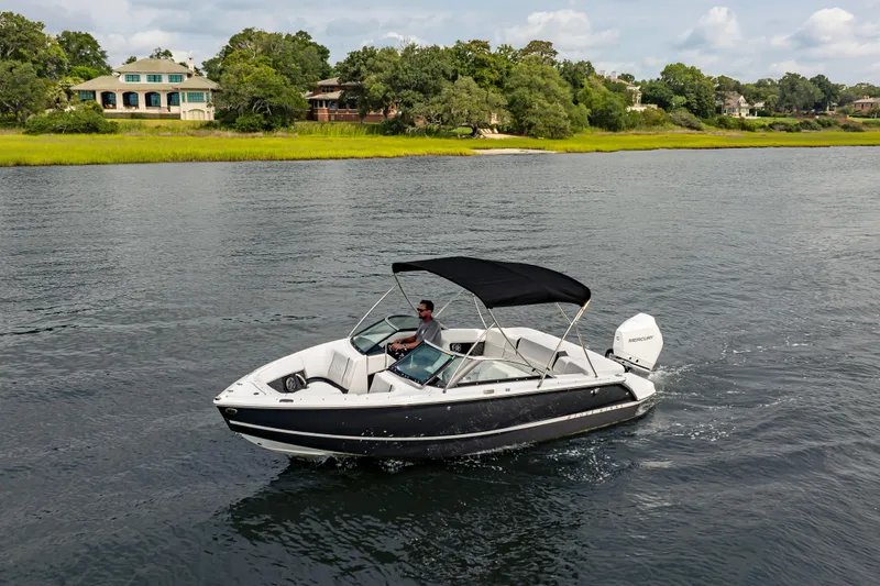 Slide: The Image of 2026 Four Winns H2 OB boat cruising on a scenic lake with lush greenery. - 11