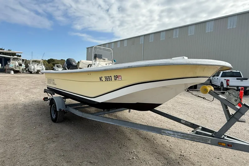 Slide: The Image of 2009 Carolina Skiff 198 DLV boat on trailer, parked outdoors near a warehouse. - 9