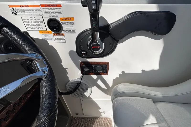 Slide: The Image of 2014 Rinker 290 Express Cruiser helm with steering wheel, throttle, and warning labels. - 12