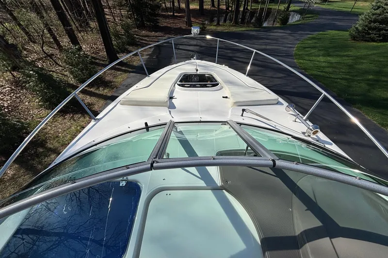 Slide: The Image of 2014 Rinker 290 Express Cruiser boat on a driveway, surrounded by trees. - 15