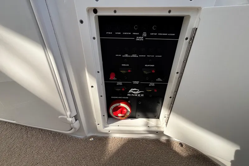 Slide: The Image of Control panel of a 2014 Rinker 290 Express Cruiser, featuring various switches and a red dial. - 19