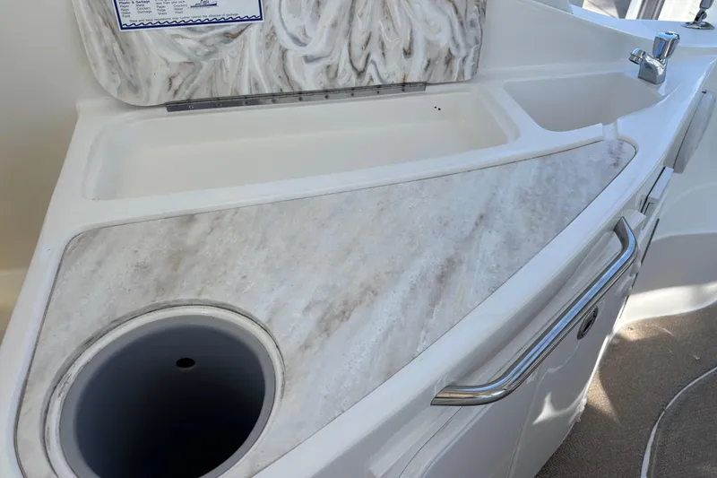 Slide: The Image of 2014 Rinker 290 Express Cruiser sink and countertop detail with faucet and storage. - 21