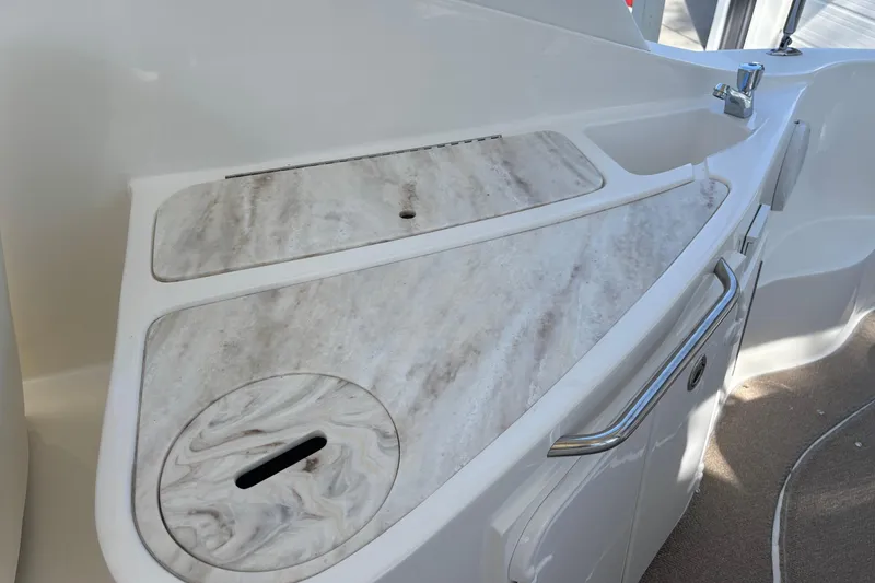 Slide: The Image of 2014 Rinker 290 Express Cruiser boat kitchenette with marble countertop and sink. - 22