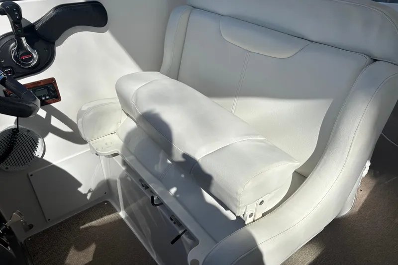 Slide: The Image of 2014 Rinker 290 Express Cruiser helm seat with white upholstery and control panel. - 23