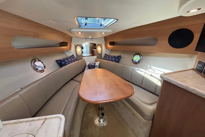 Slide: The Image of 2014 Rinker 290 Express Cruiser interior with elegant seating and wooden table. - 3