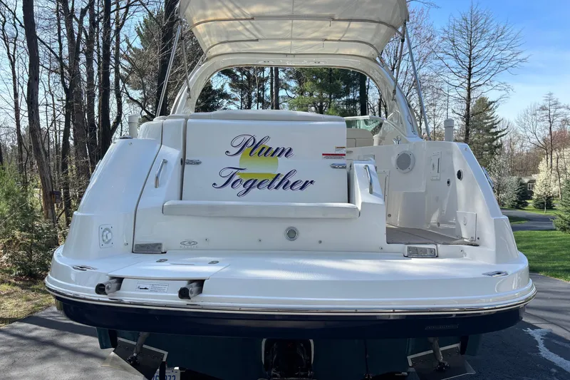 Slide: The Image of 2014 Rinker 290 Express Cruiser with "Plum Together" text on the back, parked outdoors. - 30