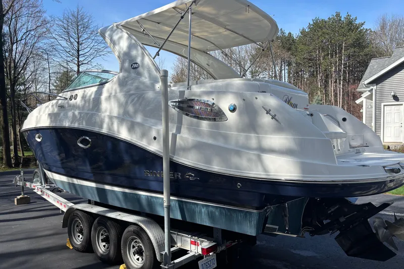 Slide: The Image of 2014 Rinker 290 Express Cruiser on trailer, parked outdoors near trees and a house. - 34