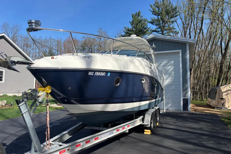 Slide: The Image of 2014 Rinker 290 Express Cruiser on trailer, parked near a garage, surrounded by trees. - 38