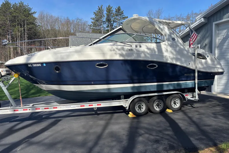 Slide: The Image of 2014 Rinker 290 Express Cruiser on trailer, parked outdoors near a garage. - 39
