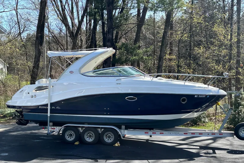 Slide: The Image of 2014 Rinker 290 Express Cruiser on trailer, parked in wooded area. - 42