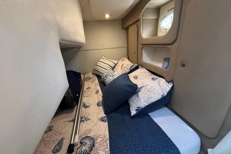 Slide: The Image of Cozy cabin interior of 2014 Rinker 290 Express Cruiser with nautical-themed bedding. - 6