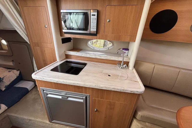 Slide: The Image of 2014 Rinker 290 Express Cruiser interior kitchen with microwave, stove, and sink. - 7