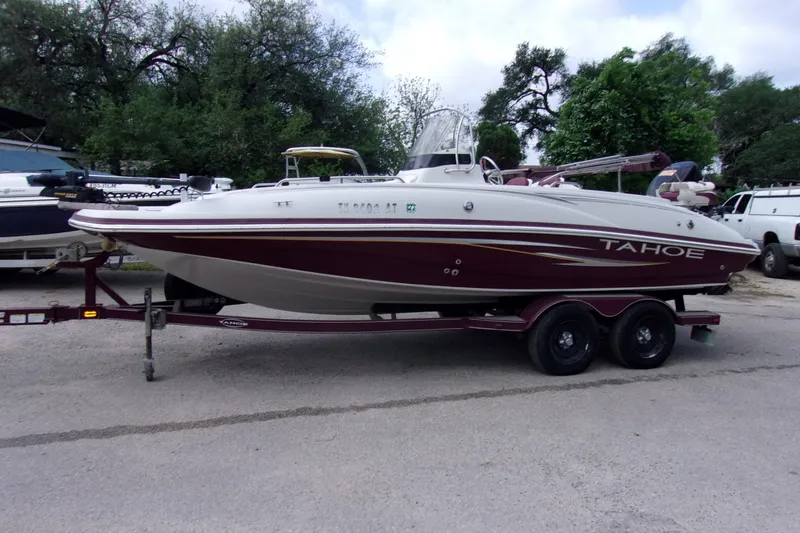 The Image of 2008 Tahoe 215 CC boat on trailer, parked outdoors with trees in background. - 1