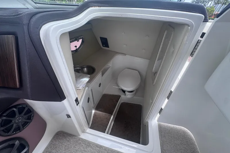 Slide: The Image of Interior of 2013 Cobalt 296 boat showing compact bathroom with toilet and sink. - 28