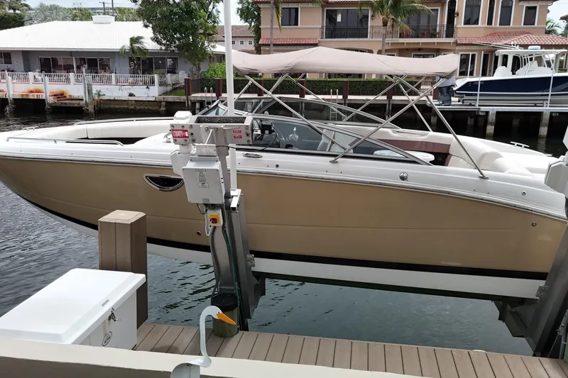 Slide: The Image of 2013 Cobalt 296 boat docked, featuring a beige hull and canopy, in a residential marina. - 3
