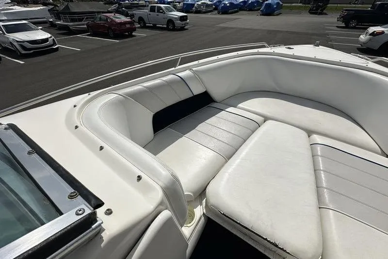 Slide: The Image of 1994 Sea Ray 220 Overnighter Signature boat with white cushioned seating in a parking lot. - 9