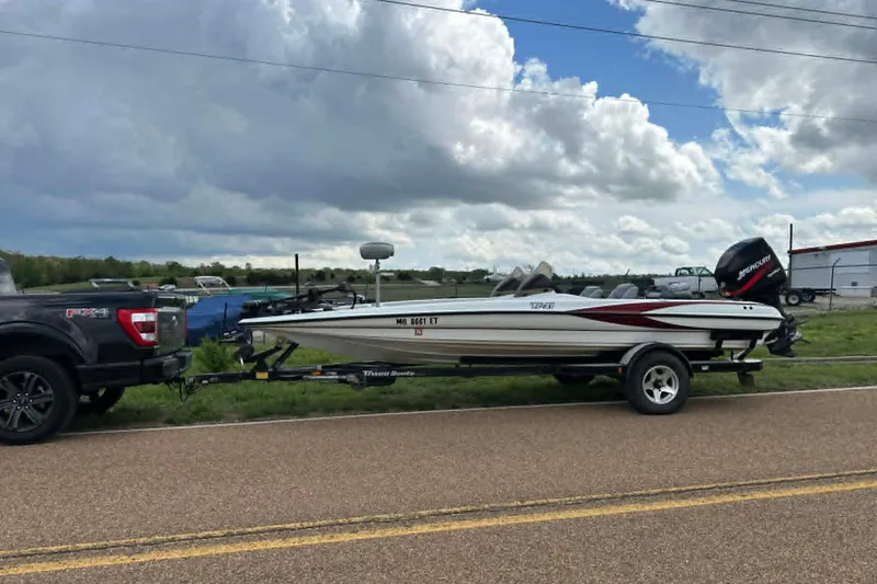 Slide: The Image of 2001 Triton Tr-21 Executive DC boat on trailer, hitched to a truck, under cloudy sky. - 14