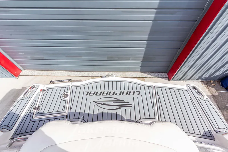 Slide: The Image of 2012 Chaparral 226 SSi boat swim platform with logo, docked near a metal garage door. - 10