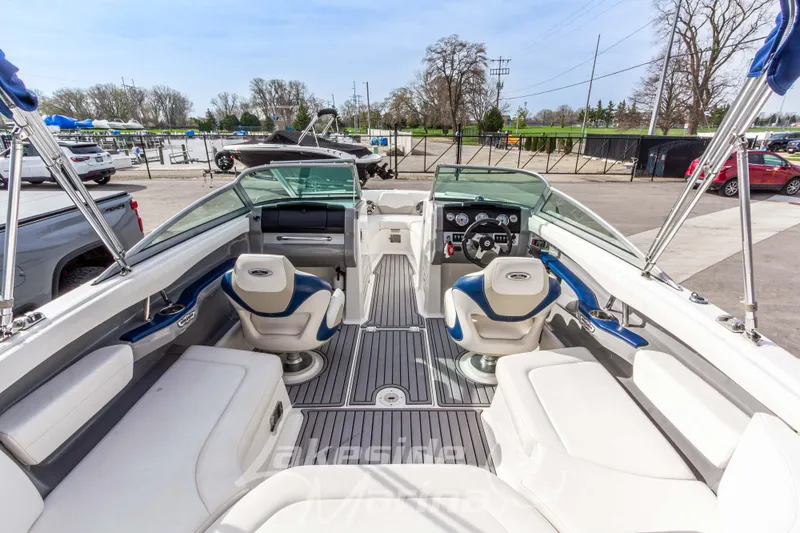 Slide: The Image of 2012 Chaparral 226 SSi boat interior with seating and steering wheel, parked outdoors. - 16