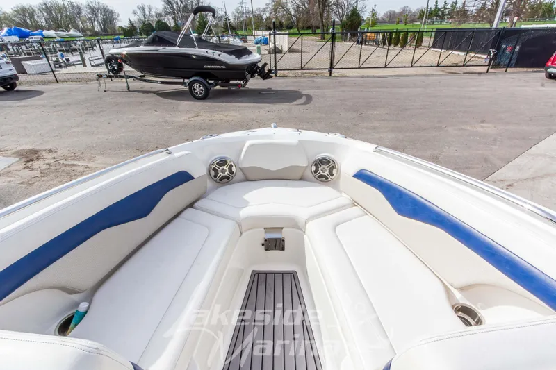 Slide: The Image of 2012 Chaparral 226 SSi boat interior with white and blue seating, docked outdoors. - 34