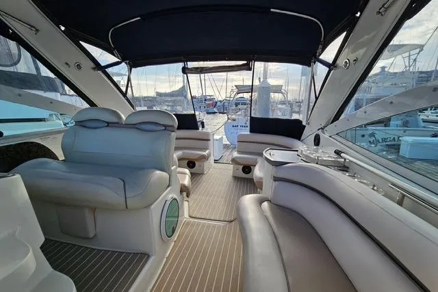 Slide: The Image of Interior view of a 1999 Doral 360se yacht with luxurious seating and marina backdrop. - 12