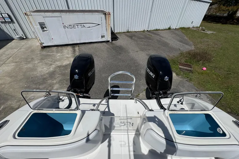 Slide: The Image of 2023 Insetta 35 IFC boat with dual Suzuki outboard motors, docked near a warehouse. - 12
