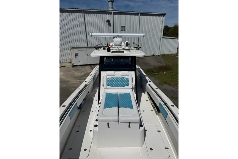 Slide: The Image of 2023 Insetta 35 IFC boat with blue and white seating, docked near a metal building. - 3