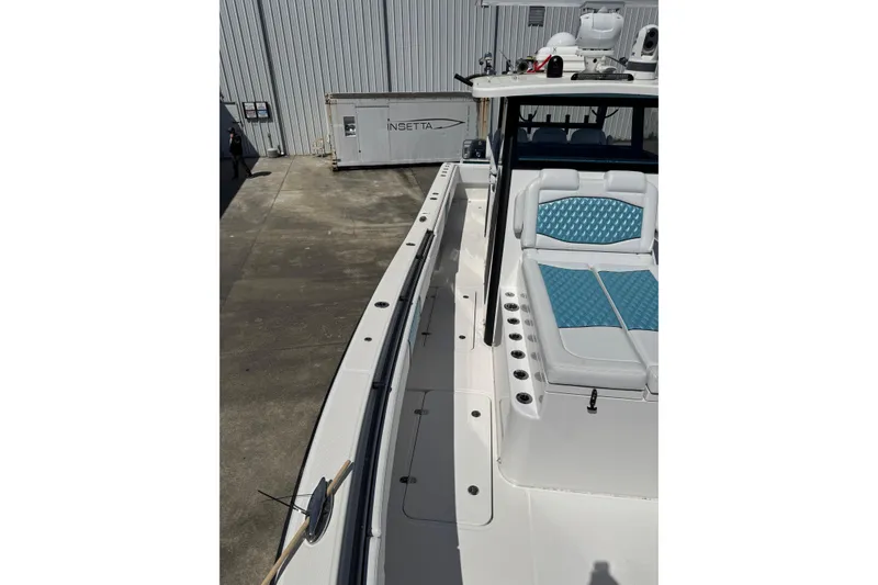 Slide: The Image of 2023 Insetta 35 IFC boat with blue seating, docked near a warehouse. - 4