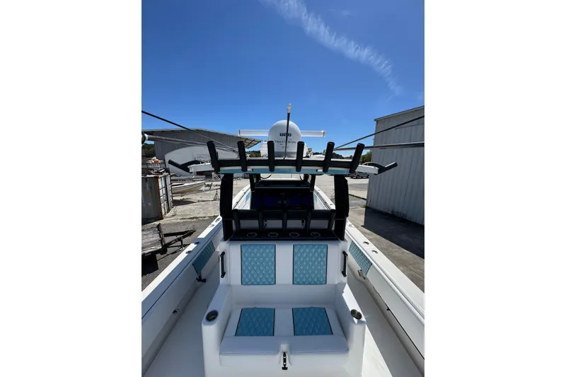 Slide: The Image of 2023 Insetta 35 IFC boat with blue seating and rod holders under clear sky. - 9