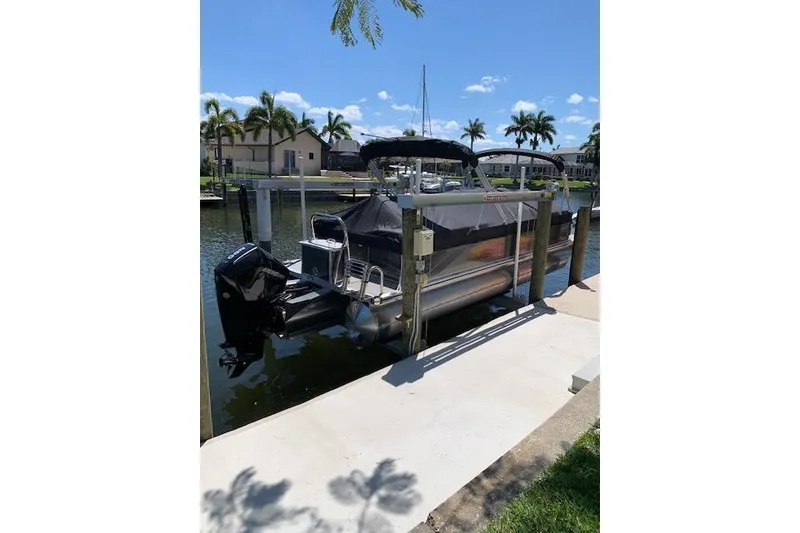 Slide: The Image of 2025 Avalon 2585 Venture QL Tri-Toon docked by waterfront with palm trees. - 1