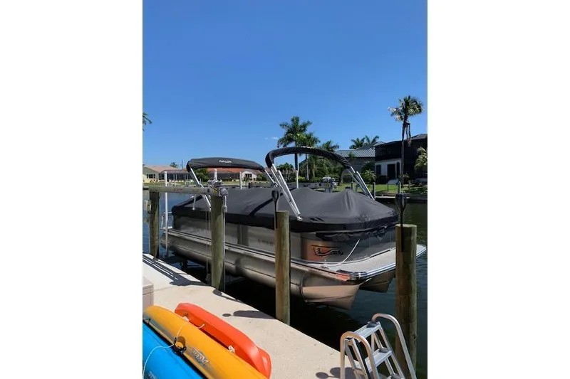 Slide: The Image of 2025 Avalon 2585 Venture QL High Performance Tri-Toon docked by waterfront homes. - 2