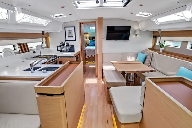 Slide: The Image of 2026 Jeanneau TH33 yacht anchored near rocky coastline with people swimming and relaxing. - 2