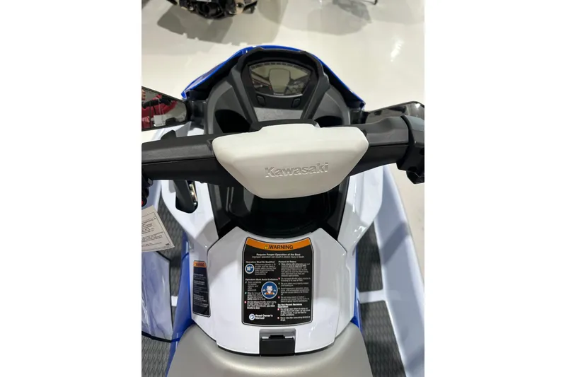 Slide: The Image of 2024 Kawasaki JN1500CRFNN jet ski dashboard with handlebars and warning labels. - 7