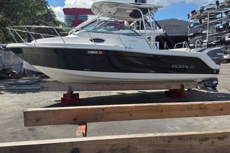 The Image of 2008 Robalo R265 Walkaround boat on dry dock, featuring sleek black and white design. - 0