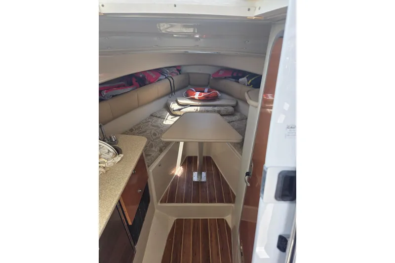Slide: The Image of 2008 Robalo R265 Walkaround cabin interior with seating, table, and kitchenette. - 12