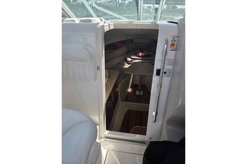 Slide: The Image of 2008 Robalo R265 Walkaround cabin interior with seating and table, viewed from entrance. - 9