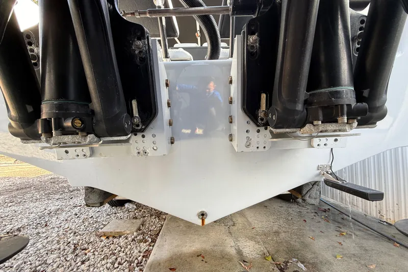 Slide: The Image of 1989 Wellcraft 302 Scarab boat stern with dual outboard motors on a gravel surface. - 17