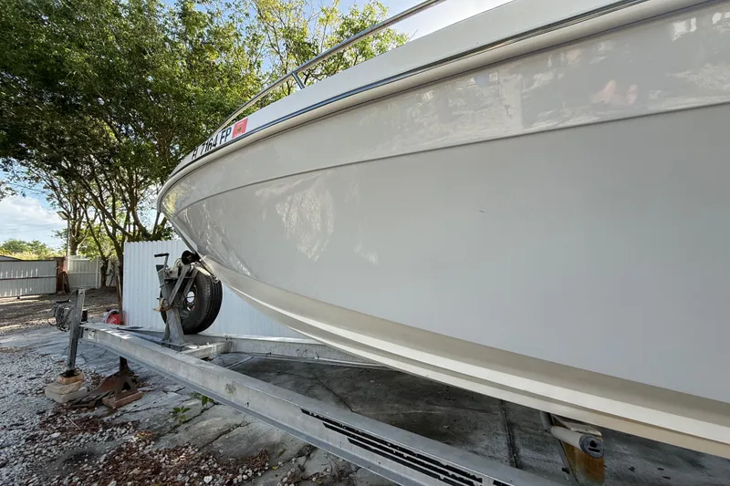 Slide: The Image of 1989 Wellcraft 302 Scarab boat on trailer, surrounded by trees and fencing. - 25