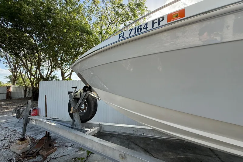 Slide: The Image of 1989 Wellcraft 302 Scarab boat on trailer, Florida registration, surrounded by trees. - 26