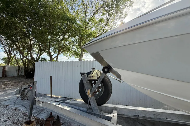Slide: The Image of 1989 Wellcraft 302 Scarab boat on trailer, parked outdoors near trees and fence. - 27