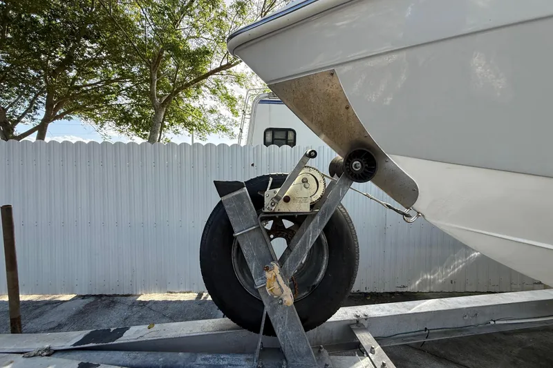 Slide: The Image of 1989 Wellcraft 302 Scarab boat on trailer, parked near white fence and trees. - 28