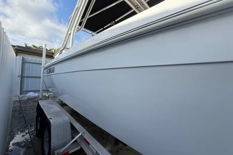 Slide: The Image of 1989 Wellcraft 302 Scarab boat on trailer, side view, with clear sky background. - 35