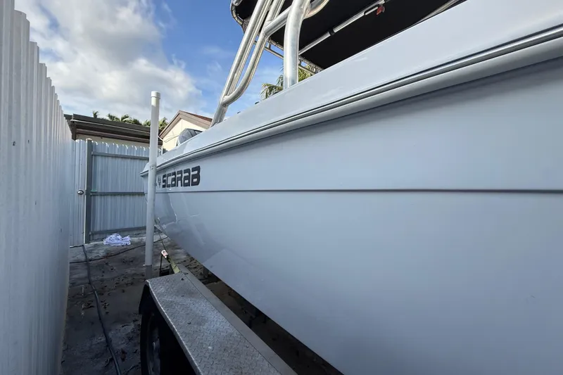 Slide: The Image of 1989 Wellcraft 302 Scarab boat on trailer, side view, near white fence. - 36