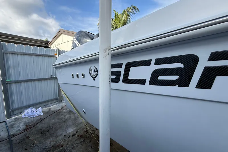 Slide: The Image of 1989 Wellcraft 302 Scarab boat with logo, parked near a fence under a blue sky. - 38