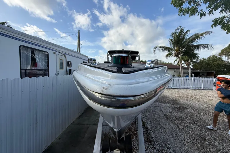 Slide: The Image of 1989 Wellcraft 302 Scarab boat on trailer, parked beside a white fence and mobile home. - 41